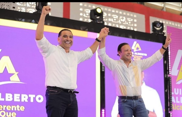 Abel Martínez, candidato presidencial del PLD, levanta los brazos a Luis Alberto Tejeda, luego de ser juramentado como candidato a alcalde de Santo Domingo Este